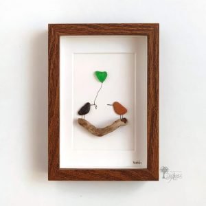 Cuadro de decoración con piedras hecho a mano con materiales recogidos del suelo en playas de Barcelona cristales del mar, madera de deriva guijarros dos pajaritos diciendo Hola UdanasArt