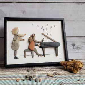 Cuadro de decoración hecho a mano con guijarros piedras madera de deriva ladrillos del mar conchas marinas Profesora dando clases de piano a alumna UdanasArt